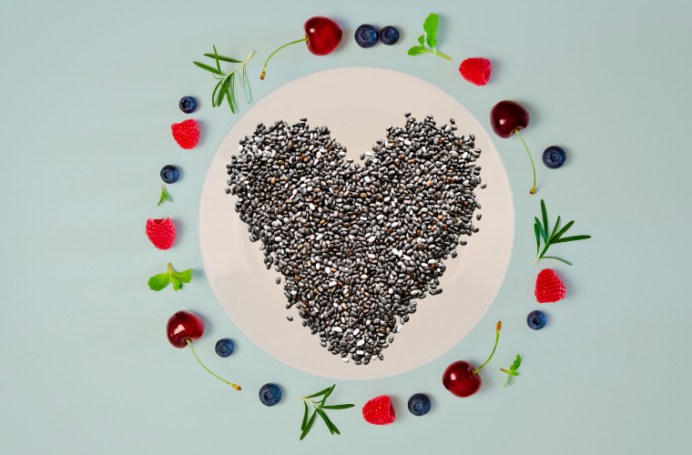image of chia seeds in a heart shape on plate surrounded by berries and herbs